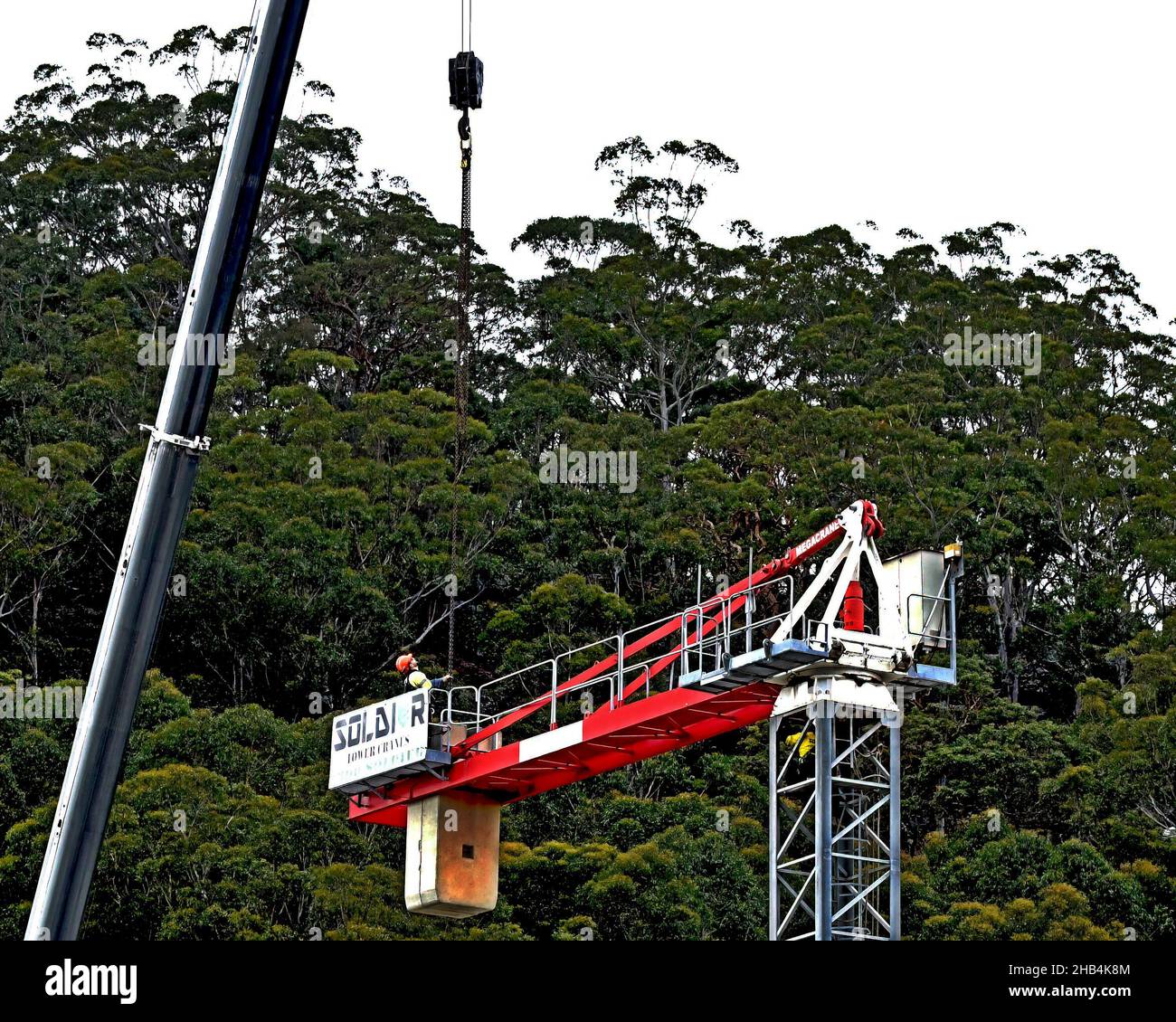 9:57 Uhr 7. Dezember 2021: Gosford, NSW, Australien. Arbeiter demontieren den Turmdrehkran vor Ort (Entfernen der Gegengewichte) auf dem fertig gestellten sozialen Netzwerk Stockfoto