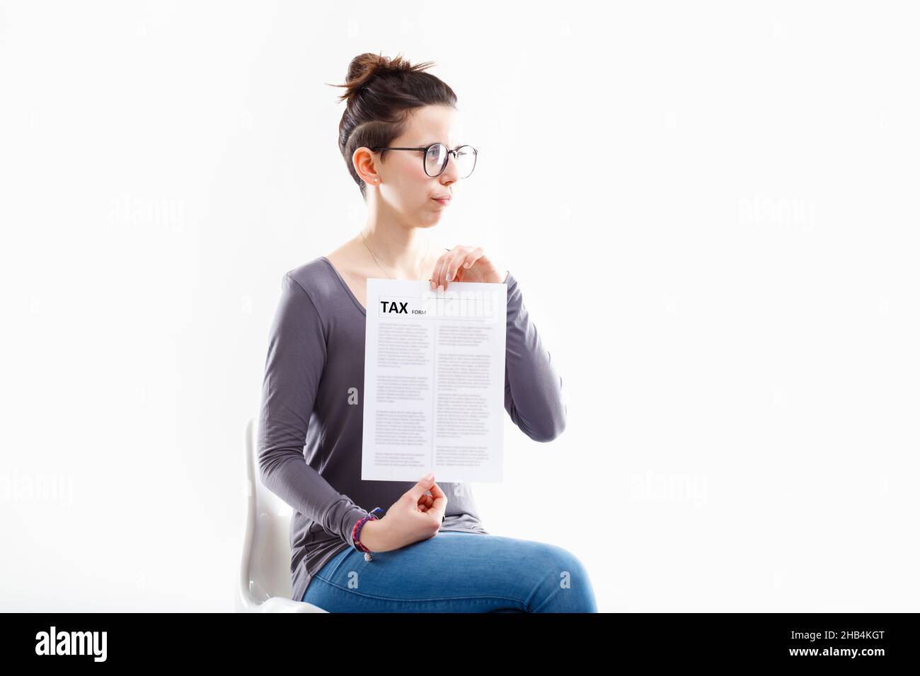 Frau definitiv nicht glücklich, hält ein Steuerformular und schaut weg in Richtung Copyspace Stockfoto