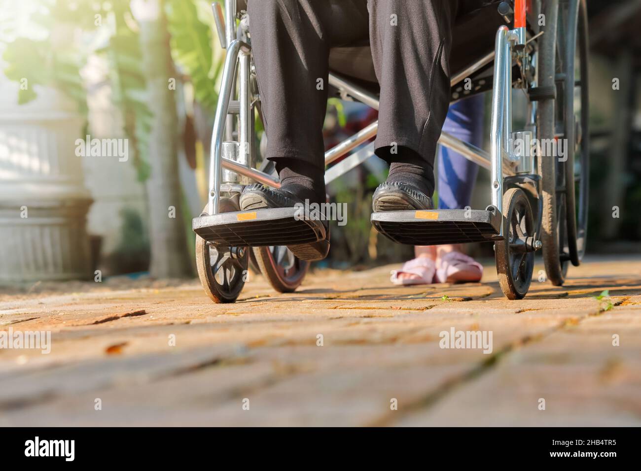 Ältere Frau im Rollstuhl, die mit der Pflegekraft läuft Stockfoto