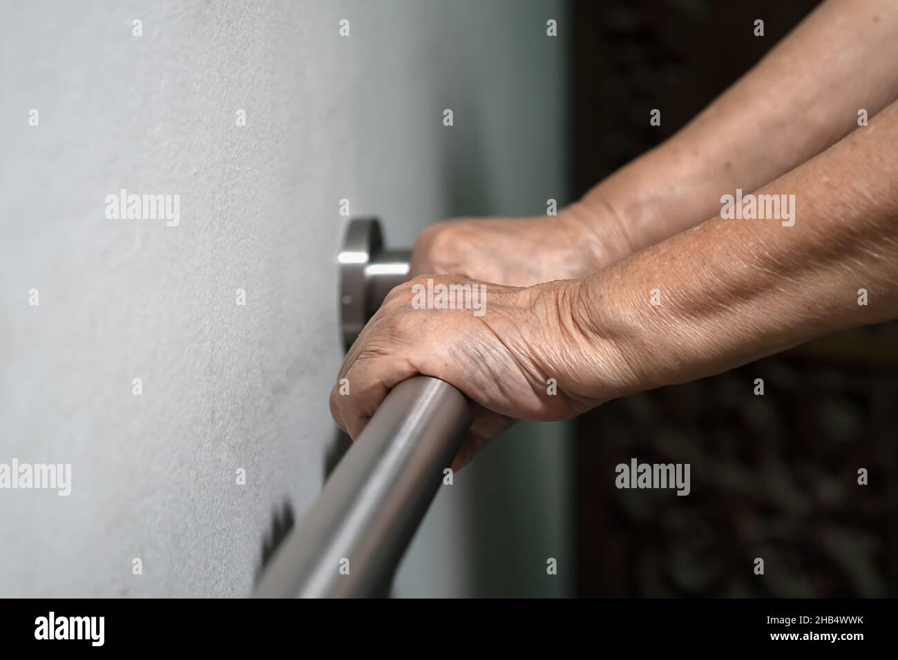 Ältere Frau, die die Hand am Handlauf hält, um das Gehen zu unterstützen Stockfoto