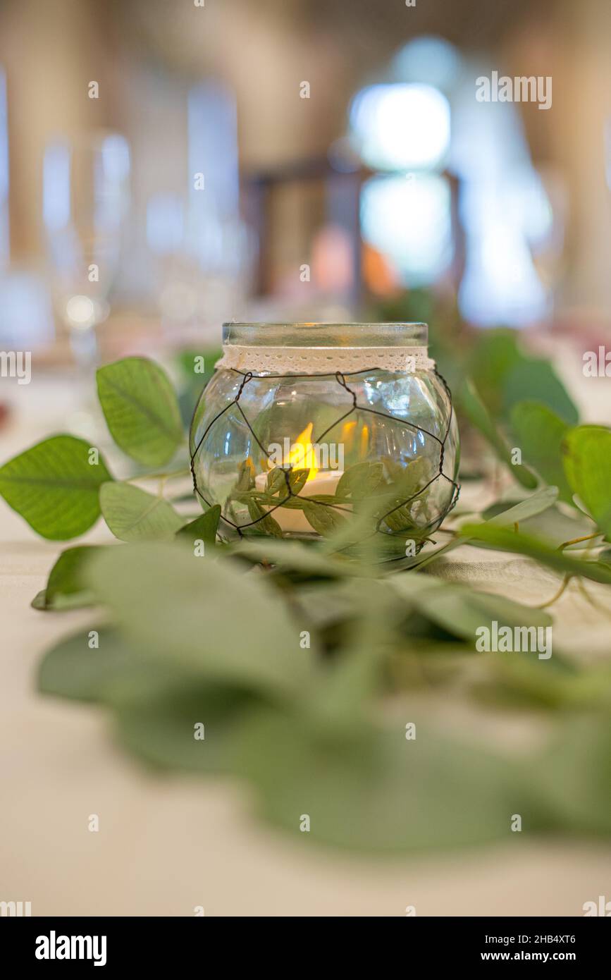 Runde Glaskerze im Mittelpunkt mit grüner Blattdekor an der Rezeption Stockfoto