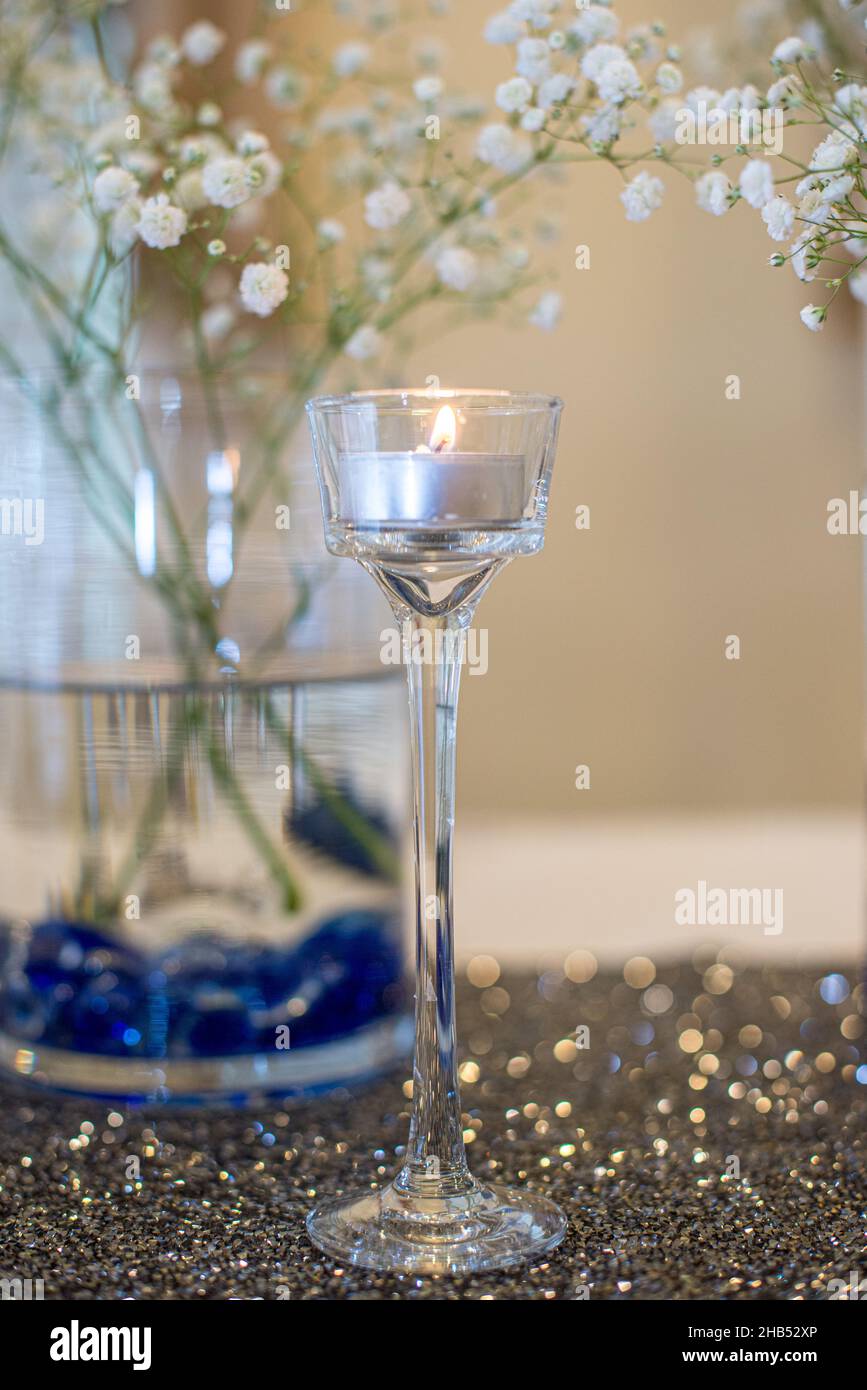 Kerzenhalter aus Glas mit brennter silberner Kerze Stockfoto