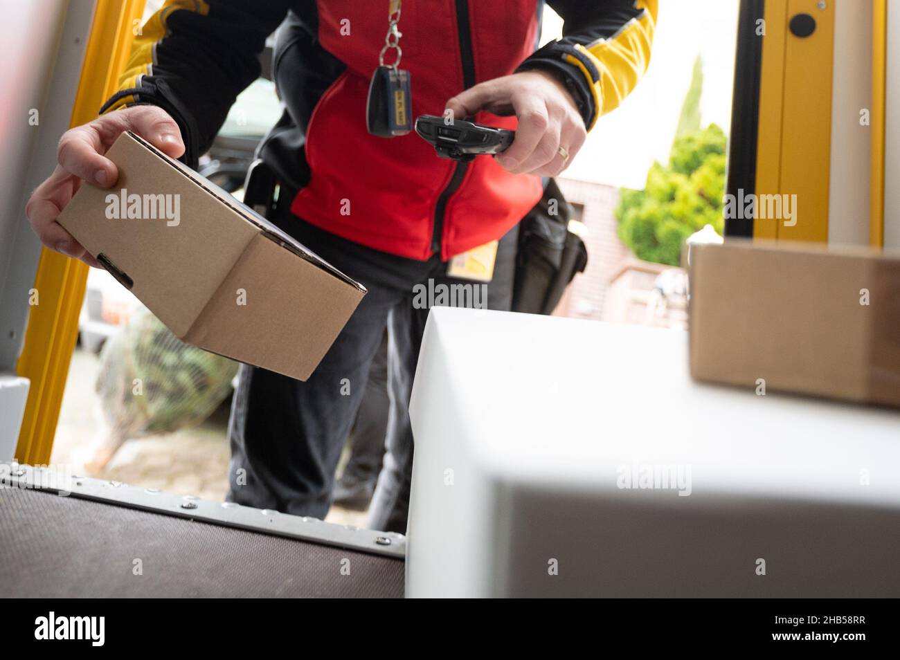 Ober Ramstadt, Deutschland. 15th Dez 2021. Ein DHL-Mitarbeiter scannt ein Paket zur Lieferung. Quelle: Sebastian Gollnow/dpa/Alamy Live News Stockfoto