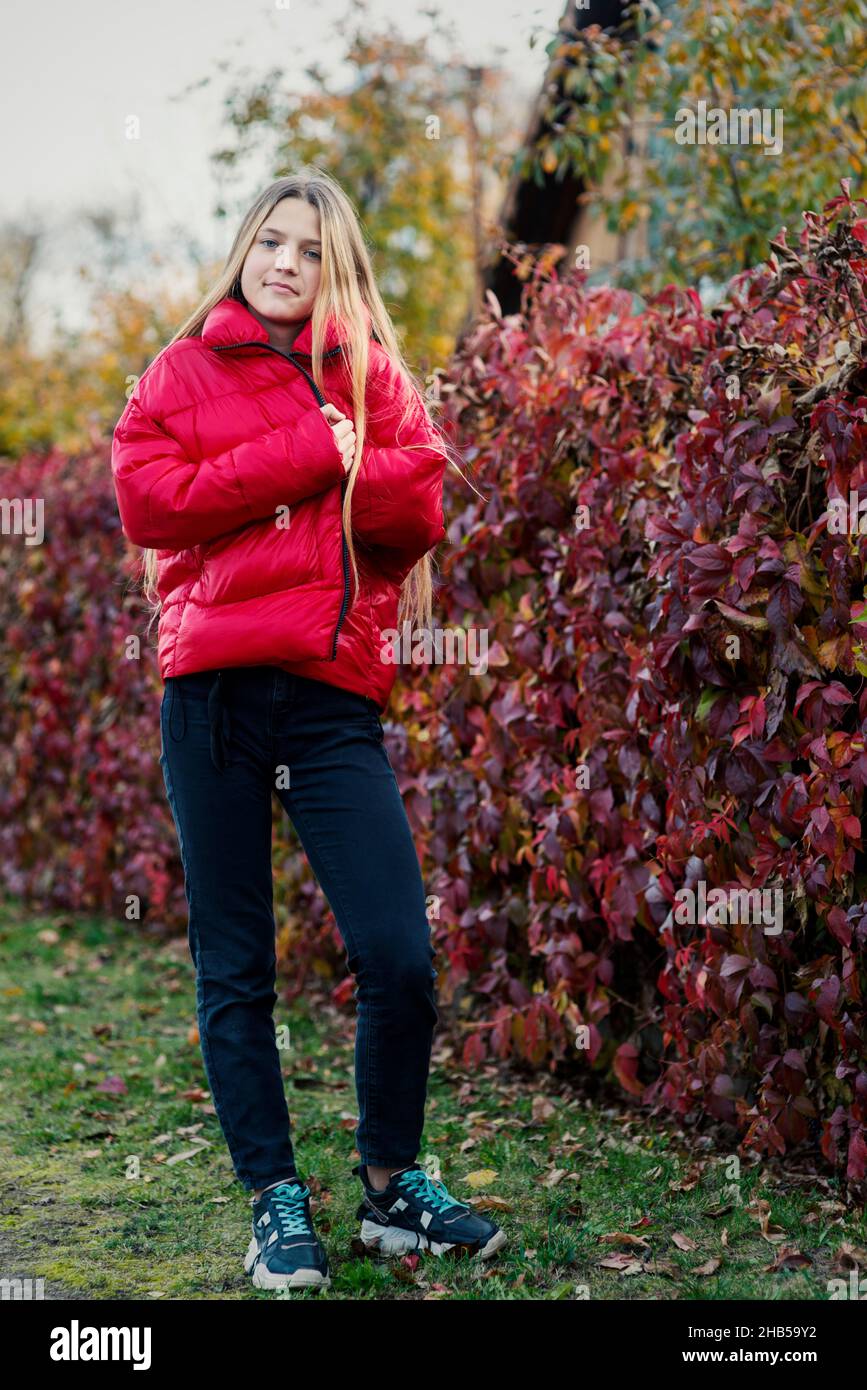 Teenager-Mädchen wickeln sich in rote Jacke im Freien bis Herbst Stockfoto