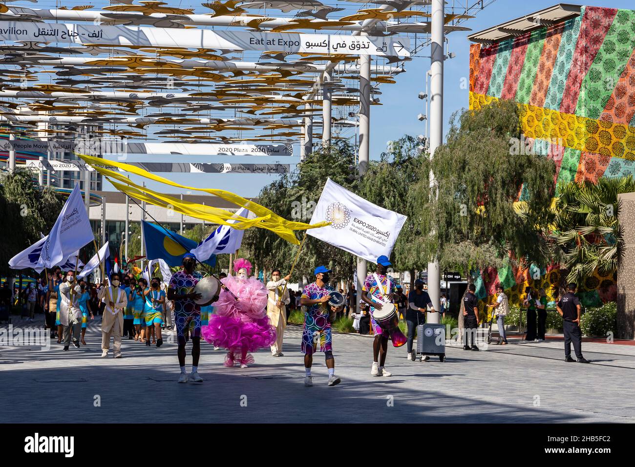 Dubai, VAE, 09.12.2021. Expo 2020 Dubai Daily Parade und Palau National Day Parade, Menschen mit bunten Expo 2020 Thema Kleidung und Fahnen, spielen mu Stockfoto