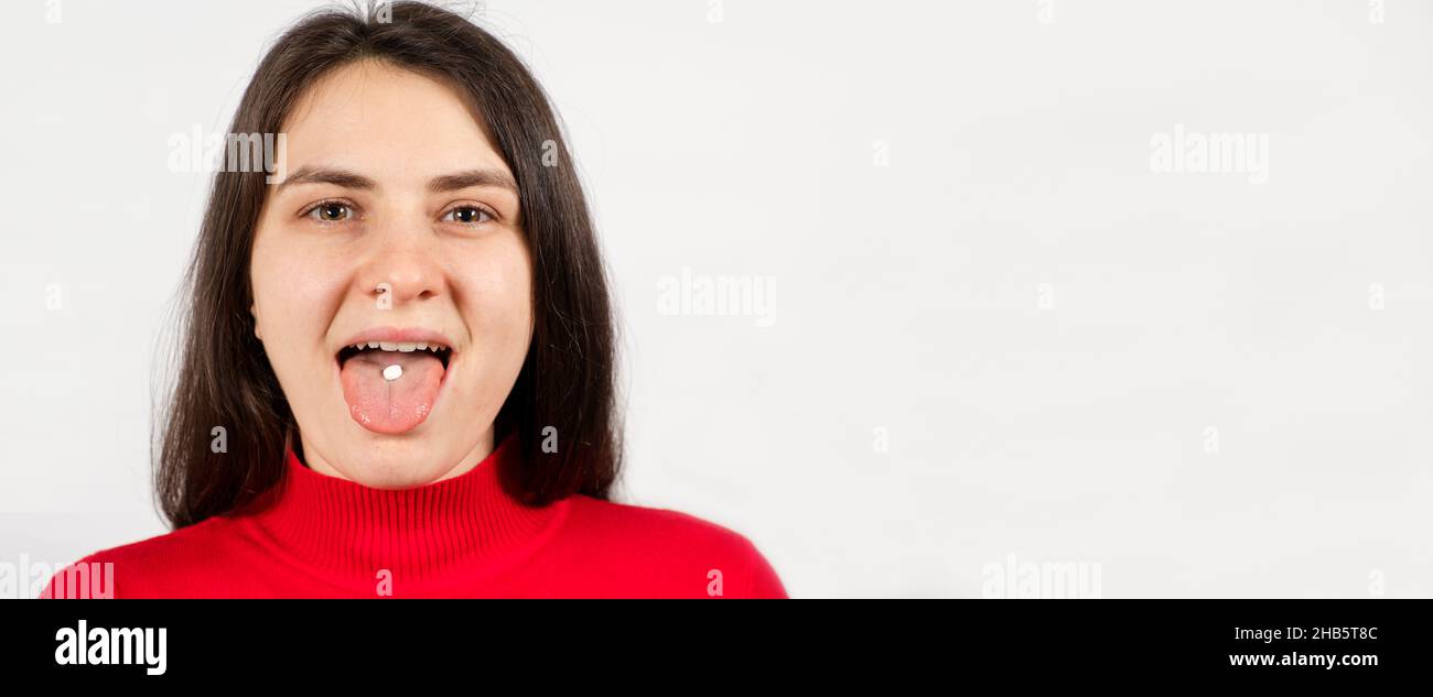 Eine Frau nimmt eine Pille, eine weiße runde Pille auf der Zunge im Mund einer Person