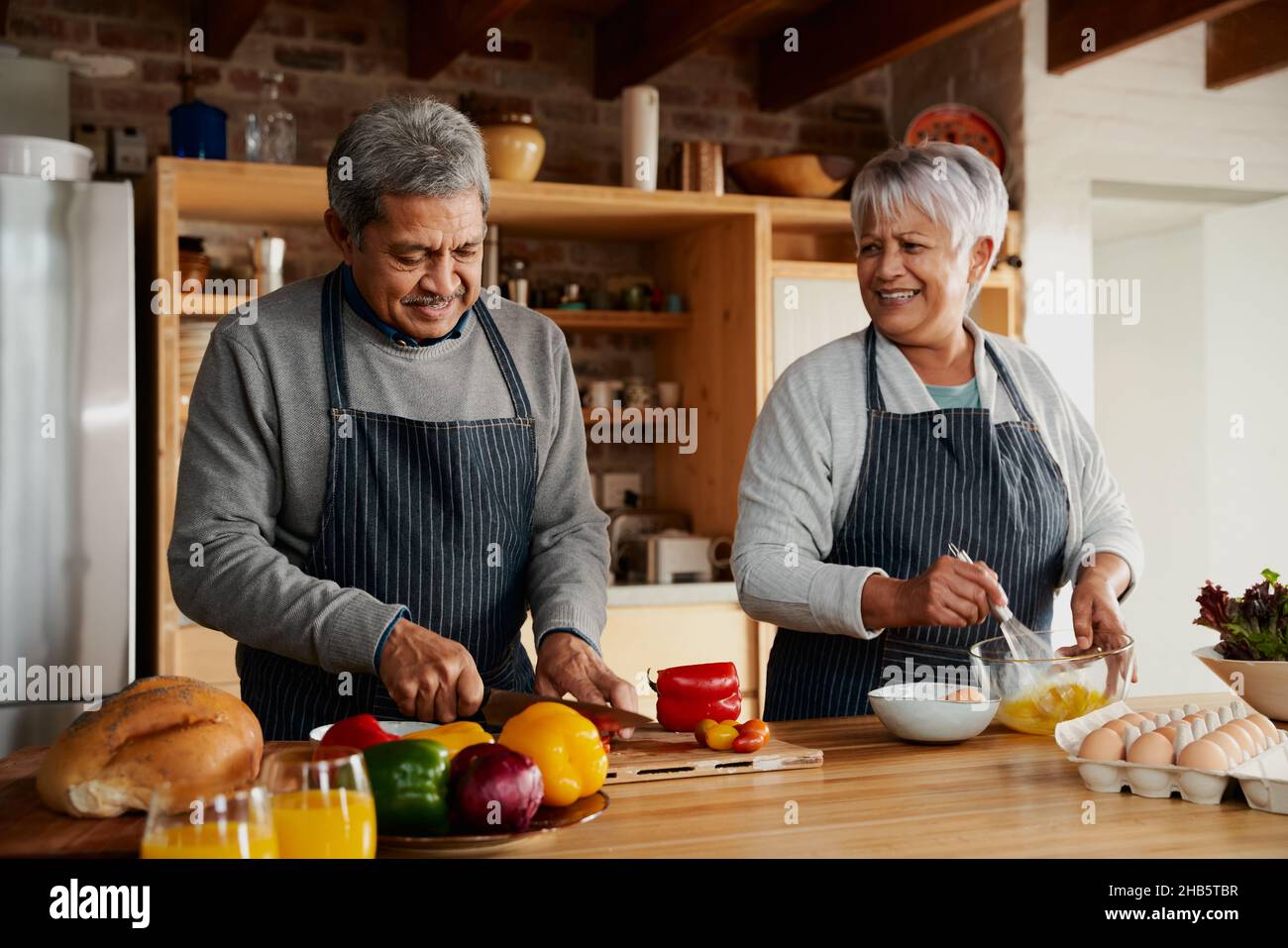 Multikulturelles älteres Paar bereitet in der modernen Küche gerne Essen zu. Gesunder Lebensstil im Ruhestand zu Hause. Stockfoto