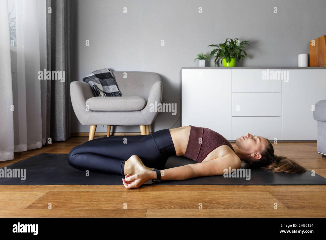 Junge Yogi-Frau, die zu Hause Yoga praktiziert. Herzöffnung Dehnung Fitness entspannende Pose Stockfoto