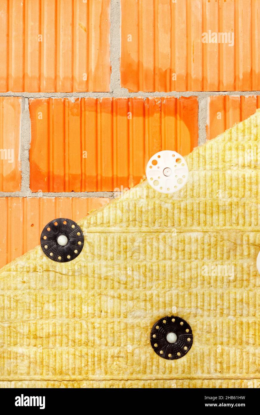 Das Fragment der Wärmedämmung der Ziegelmauer des Hauses mit der mineralischen Wolle. Stockfoto