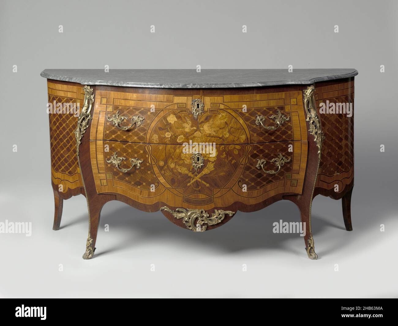 Kommode mit zwei Schubladen und einer Tür an den Seiten. Intarsien-Dekoration mit Rauten, Rosetten und Flechtwerk und Mitte zwei Tauben, Blumenarrangements, Bogen, Fackel und Pfeilköcher., Eichenkommode mit mehreren Hölzern geklebt, mit vergoldeter Bronze-Rocaille-Hardware und Marmorplatte. Die Vorderseite enthält zwei Schubladen, an den Seiten jeweils eine Tür. Die gestreckten S-förmigen Eckpfosten mit Beschlägen fügen sich in die Beine ein. Von den scalloped Bodenschienen trägt die mittlere ein großes Hardware-Stück. Die Intarsien bestehen aus Scheiben mit Rosetten, die von Flechtenbändern umrahmt sind; die mittlere Tafel zeigt zwei Tauben Stockfoto