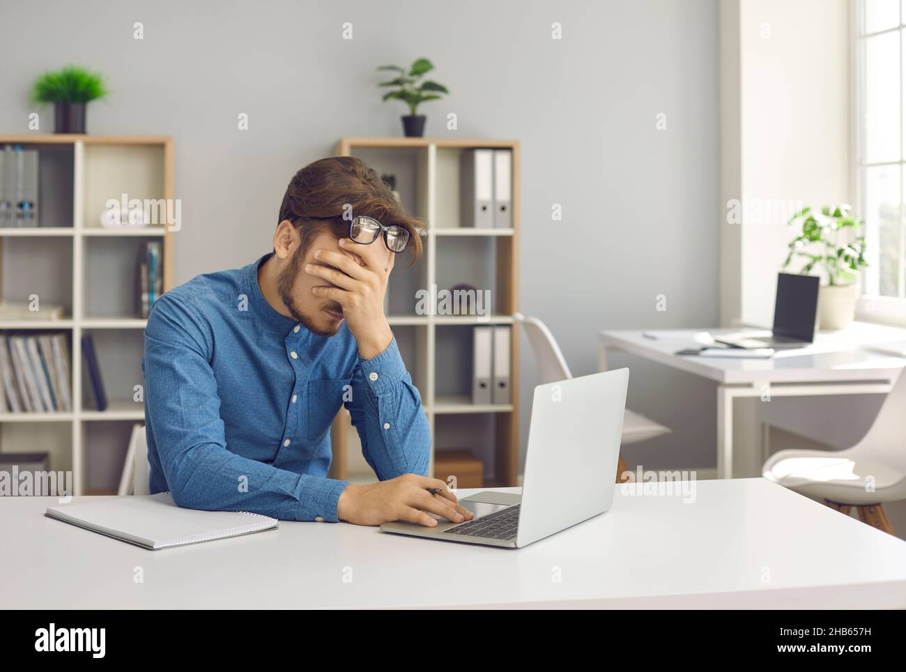 Gestresster, müder, erschöpfter Mann, der Burnout hat und mit einem Laptop am Schreibtisch sitzt Stockfoto