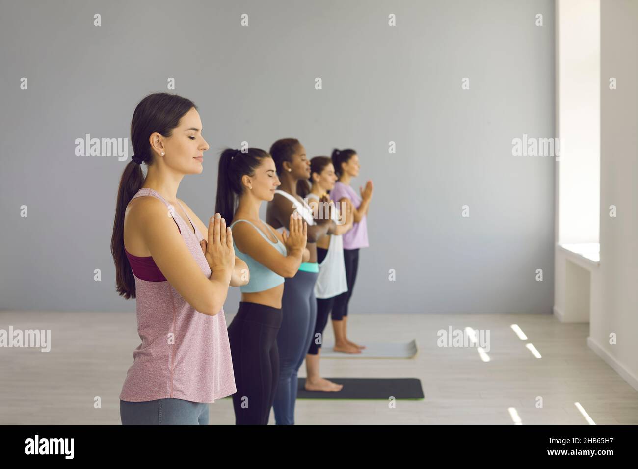 Frauen machen eine namaste Geste und meditieren mit geschlossenen Augen, um Energie wiederherzustellen. Stockfoto