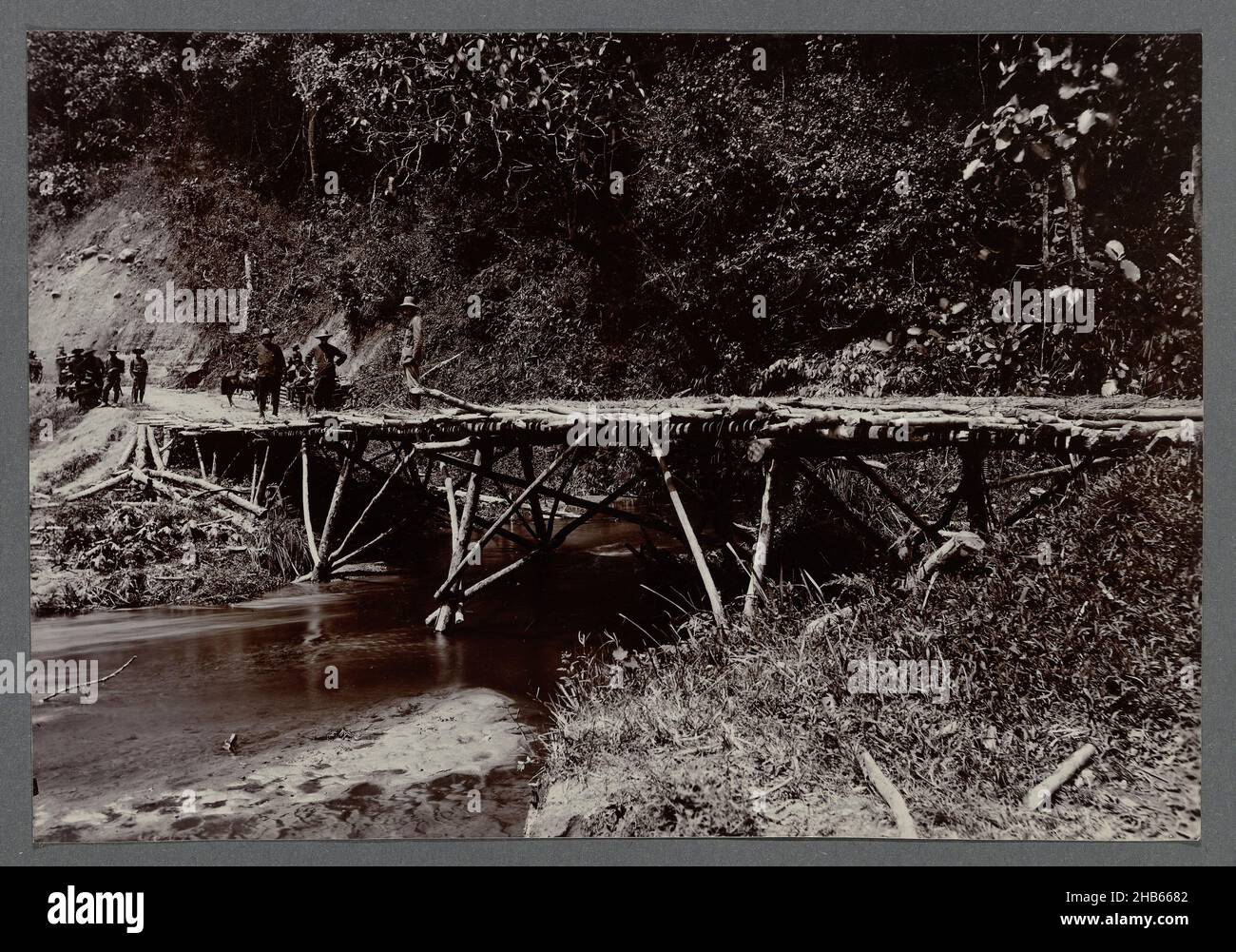 Alte Brücke, eine alte Brücke aus Holzpfosten über einen kleinen Fluss. Einfahrfoto in einem Album von 87 Fotos über den Bau der Gajo-Straße auf Nord-Sumatra zwischen Bireuen und Takinguen zwischen 1903-1914., anonym, Noord-Sumatra, 1903 - 1913, fotografische Unterstützung, Höhe 138 mm × Breite 200 mm Stockfoto