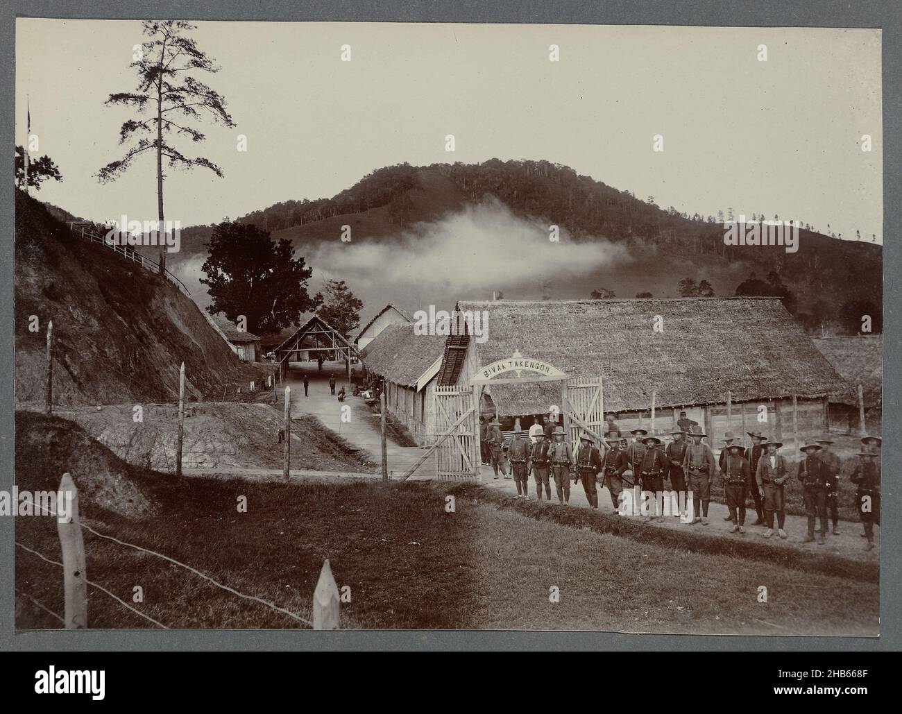 Lager Takengon, Militärpersonal, das vor dem Tor zum Biwak Takengon posiert. Eingezücktes Foto in einem Album von 87 Fotos über den Bau des Gajo Highway auf Nord-Sumatra zwischen Bireuen und Takinguen zwischen 1903-1914., anonym, Noord-Sumatra, 1910 - 1913, fotografische Unterstützung, Höhe 138 mm × Breite 200 mm Stockfoto