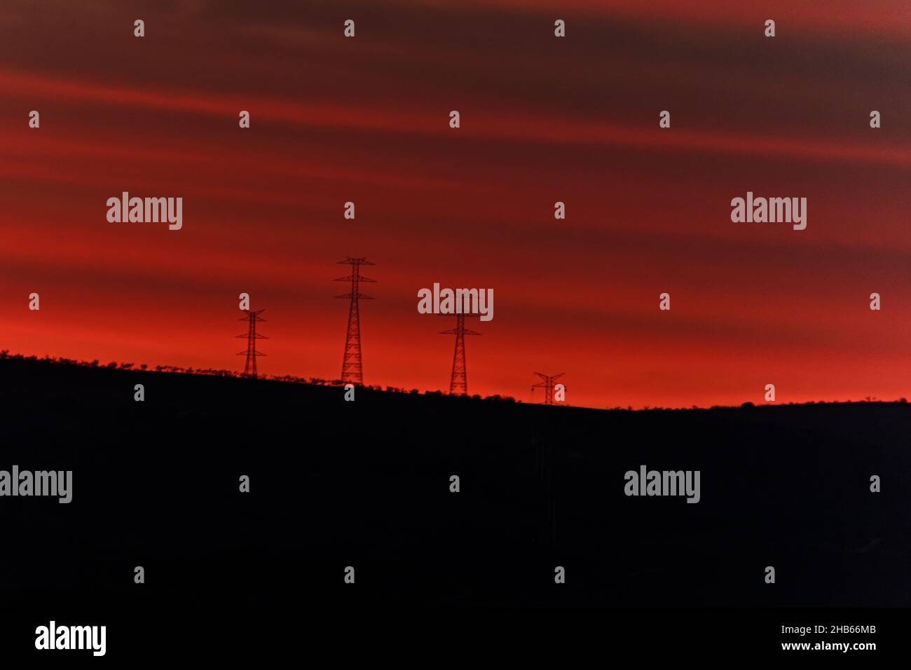 Sonnenuntergang über den Bergen, die mit elektrischen Windkraftanlagen bepflanzt sind Stockfoto