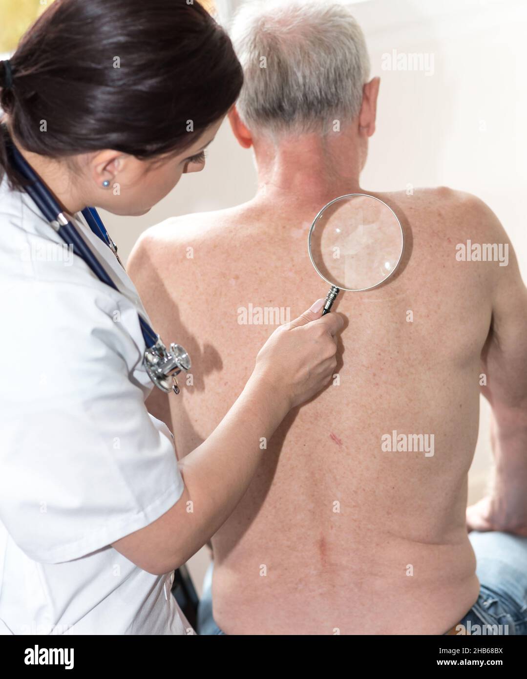 Junge Ärztin, die die Haut eines älteren Patienten untersucht Stockfoto
