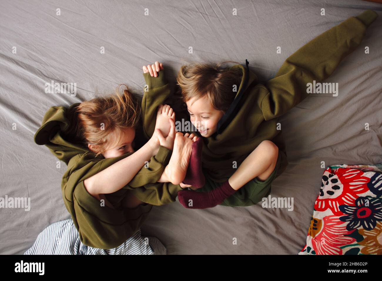 Niedliche kaukasische Kinder aus Russland spielen auf einem Bett in passender Kleidung Stockfoto