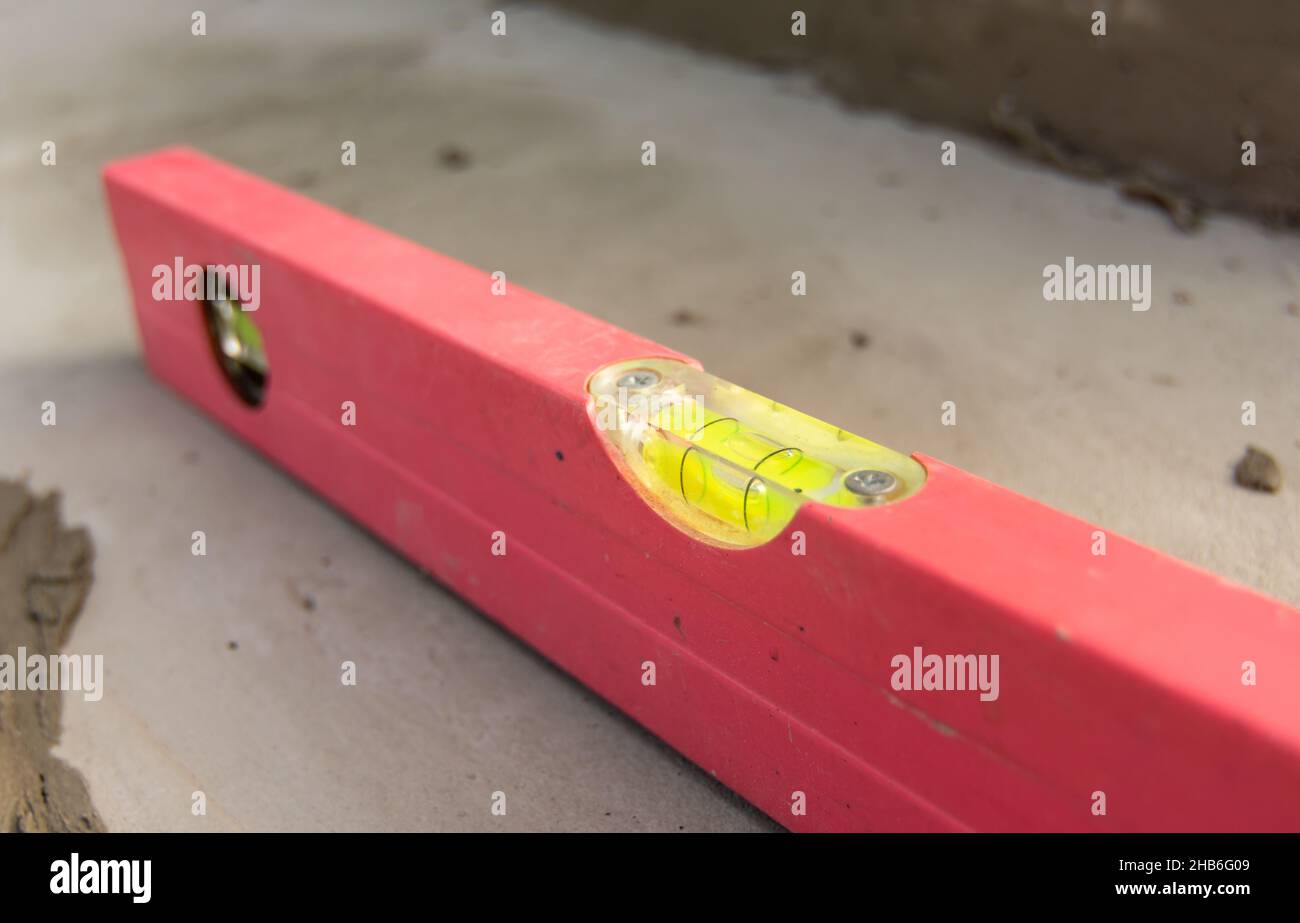 Detail einer Wasserwaage und Wasserblasen zur Messung der Ebenheit der Treppenoberfläche beim Verlegen von Pflastersteinen. Stockfoto