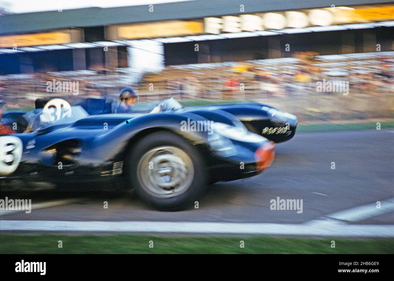 Verschwommenes Foto des britischen Sportrennfahrers Bill de Selincourt (1921-2014), der der Kamera am nächsten ist und Lister-Jaguar mit dem „geklopften“ BARC-Event Goodwood fährt, 1961. März Startschuss für das Rennen aus dem Startfeld Stockfoto