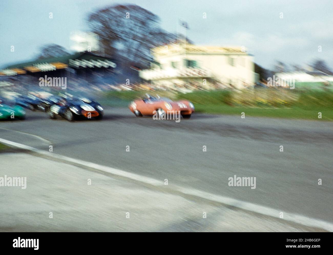 Verschwommenes Foto des britischen Sportrennfahrers Bill de Selincourt (1921-2014), der Lister-Jaguar mit dem „knobbly“-Auto 33 fuhr, BARC-Event Goodwood, 1961. März Start des Rennens, John Coundley im braunen Jaguar E-Typ Stockfoto
