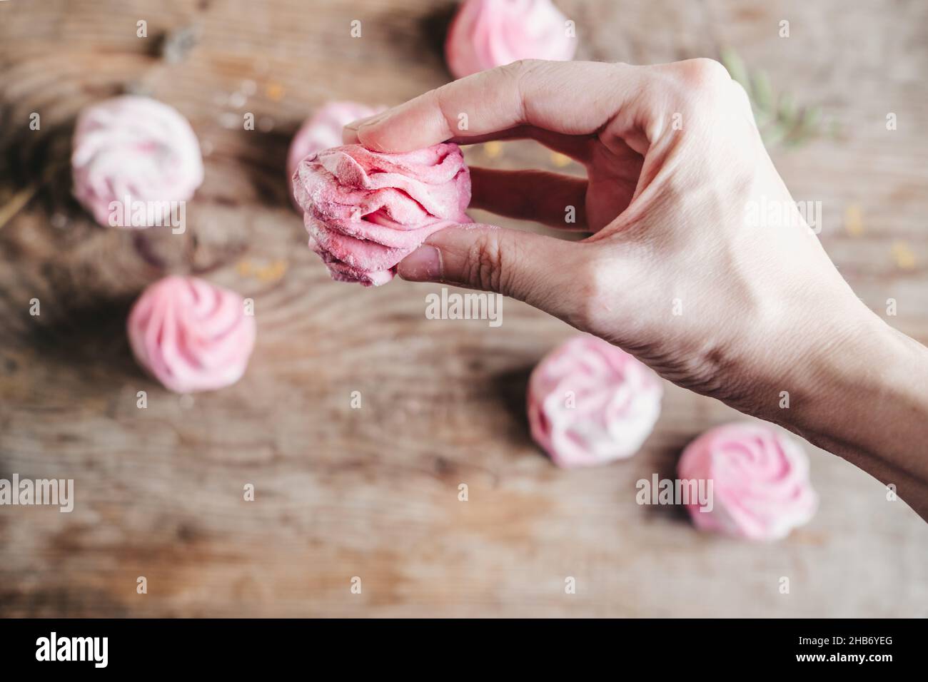 beerenmarmelibe rosa in den Händen, vor dem Hintergrund von Marschwalben auf einem Holztisch. Do-it-yourself elastisch und weich marmelow Stockfoto