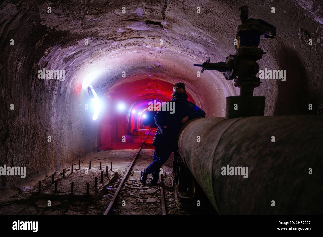 Städtischer Entdecker in Maske im unterirdischen Kommunikationstunnel. Stockfoto