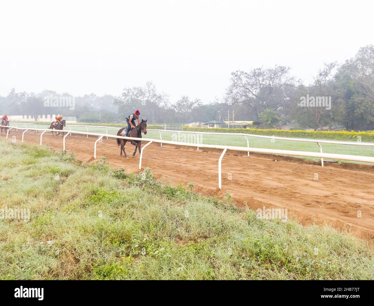 Jockeys reiten am frühen Morgen auf der Rennstrecke auf der Pune-Rennstrecke in Indien am 7. Dezember 2021 auf Rennpferden Stockfoto