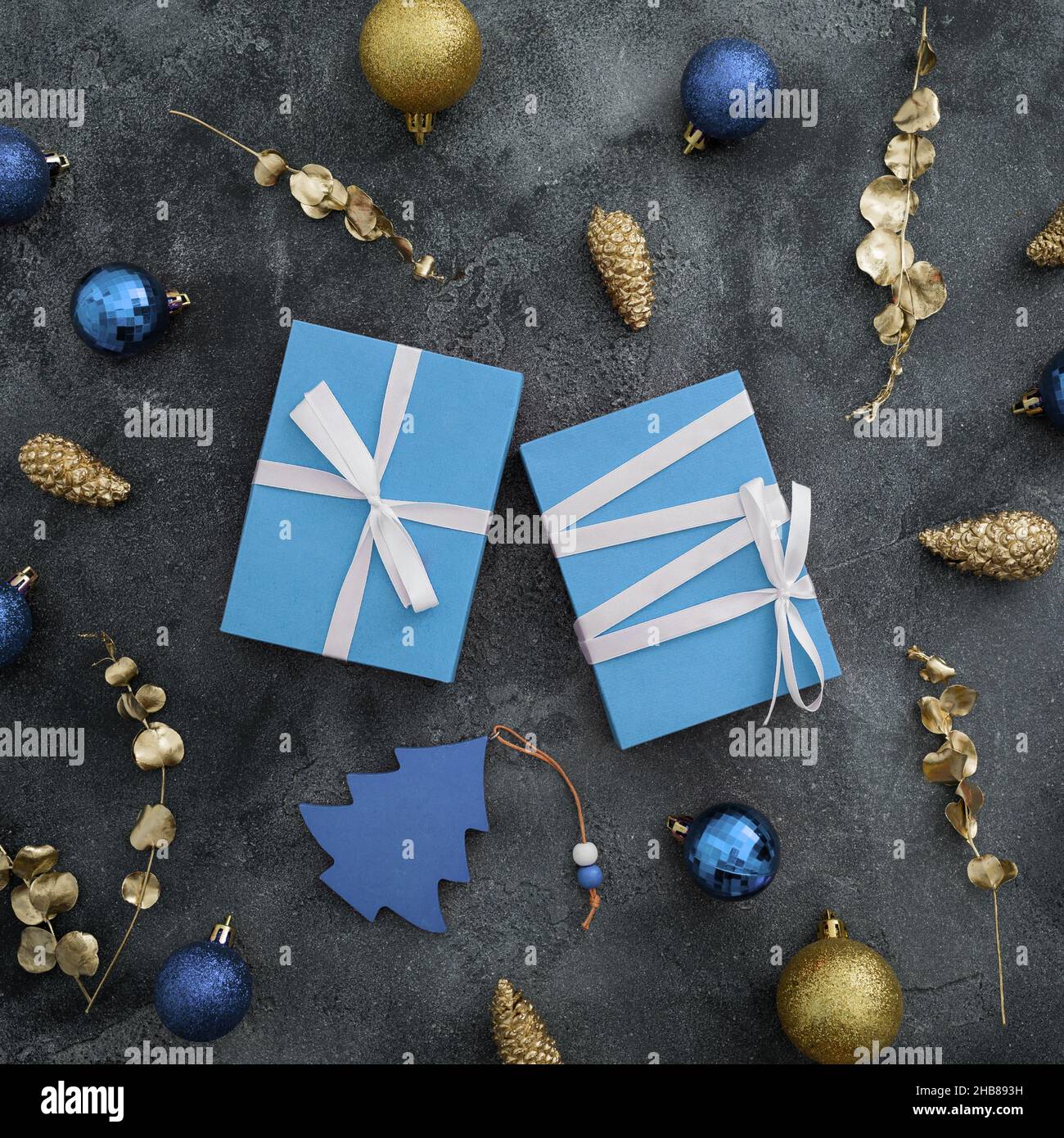 Weihnachtskonzept mit Geschenkbox und goldener Dekoration auf dunklem Hintergrund. Neujahrskonzept. Flach liegend, Draufsicht Stockfoto