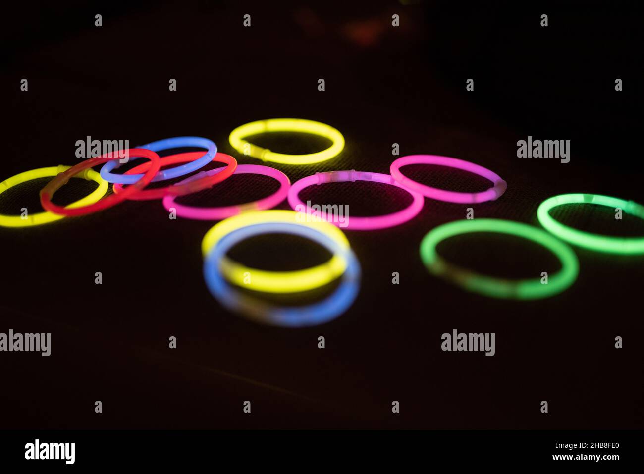 Bunte LED-Ringe leuchten auf dem schwarzen Hintergrund. Leuchtende Ringe in grün, rosa, rot, gelb, blau. Partyzubehör. Kinderspielzeug Stockfoto