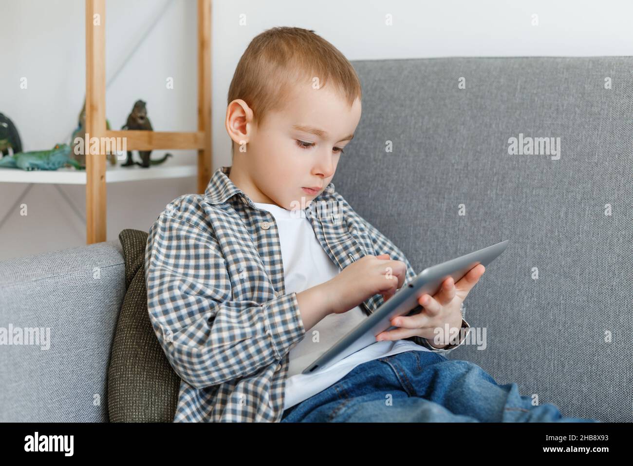 Junge ohne elterliche Kontrolle verschwenden Zeit spielen. Kind hat Spaß mit Tablet. Frühkindliche Bildung und Freizeit im Elementaralter Stockfoto