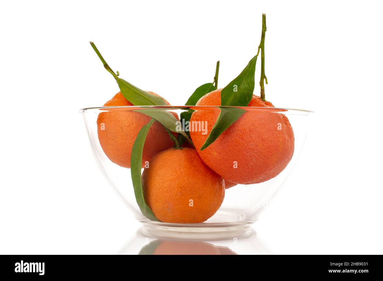 Mehrere leuchtend orange reife Mandarinen in einer Glasschale, Nahaufnahme, isoliert auf Weiß. Stockfoto