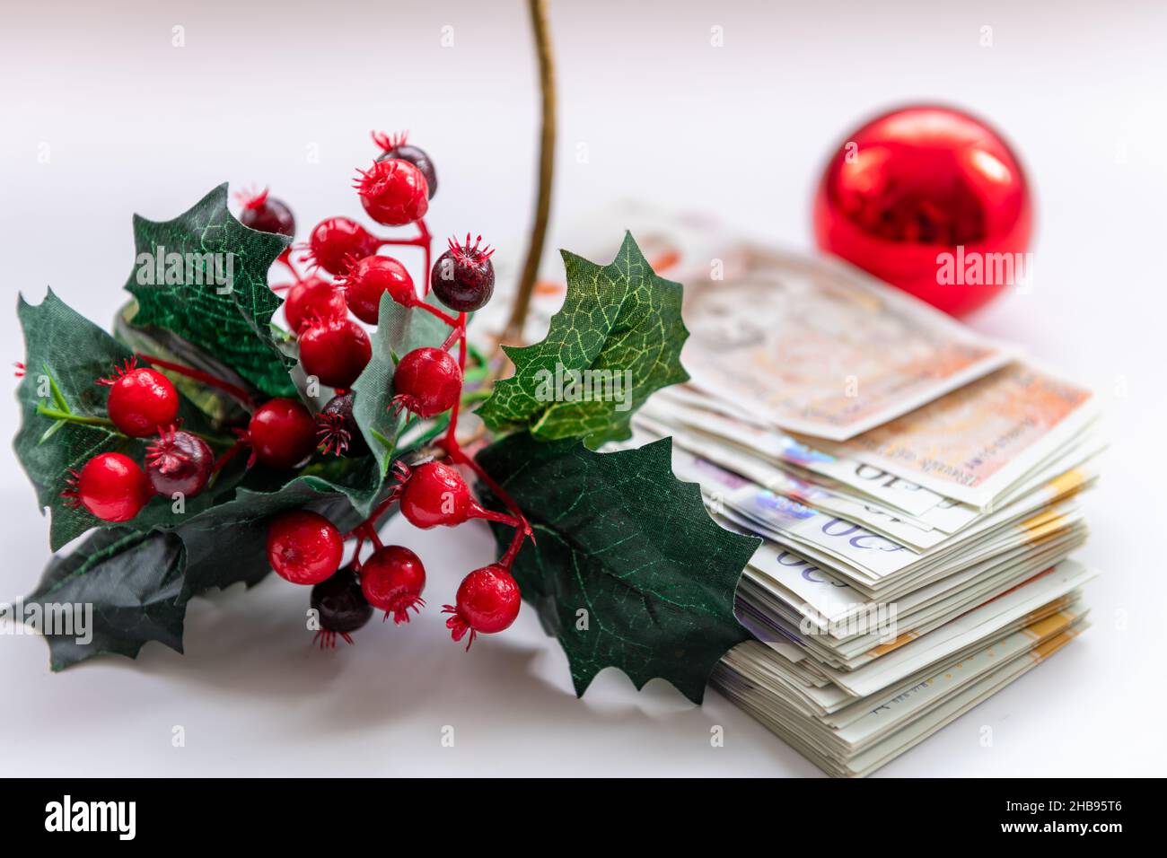 Weihnachtsdekorationen mit einem Stapel von Banknoten, isoliert auf weißem Hintergrund. Kostspieliges Weihnachtskonzept, Hintergrund. Stockfoto