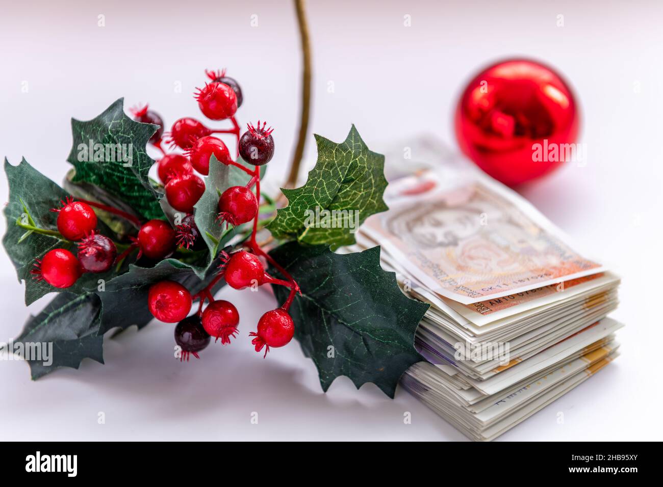 Weihnachtsdekorationen mit einem Stapel von Banknoten, isoliert auf weißem Hintergrund. Kostspieliges Weihnachtskonzept, Hintergrund. Stockfoto