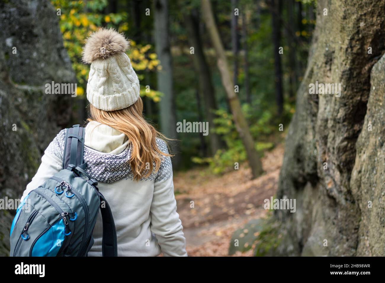 Wanderin mit Strickpullover und Hut beim Spaziergang im Herbstwald. Wandern in den Bergen. Weibliche Touristin in warmer Kleidung Stockfoto