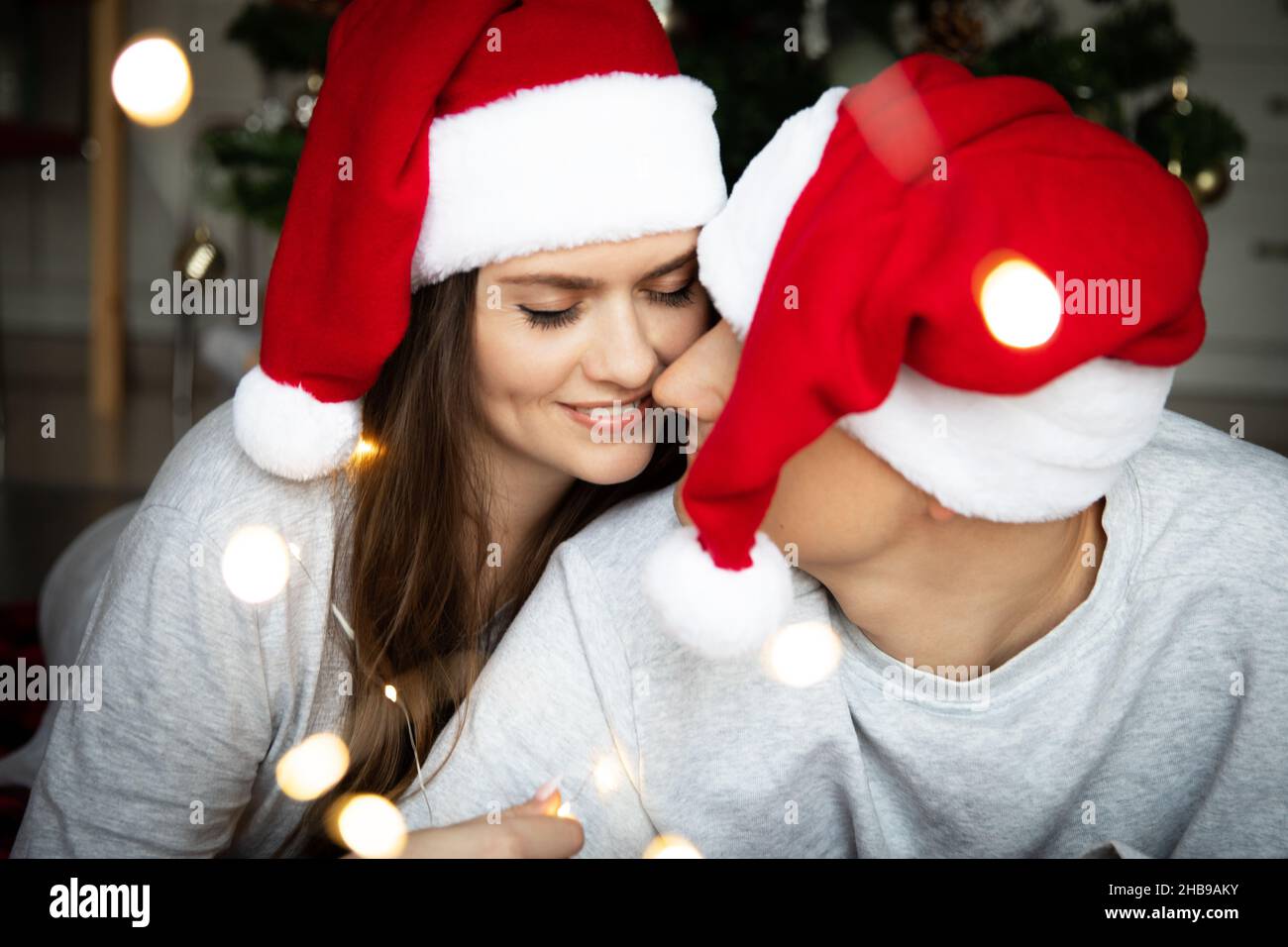 Schöne junge Frau mit langen dunklen Haaren und einem Mann in rot-weißen Santa-Hüten Stockfoto