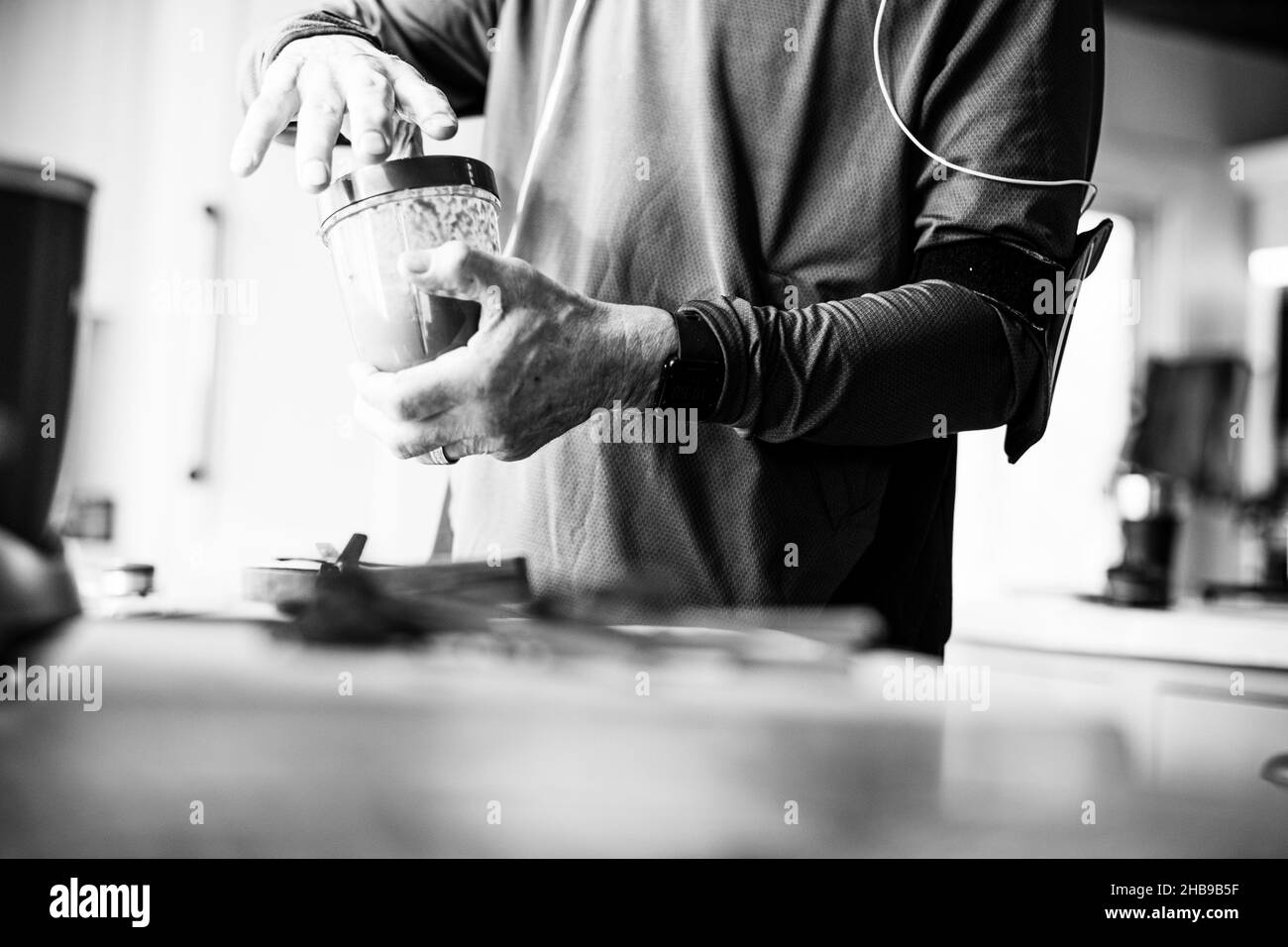 Älterer Mann, der nach einem Lauf in seiner Küche einen Smoothie zubereitet Stockfoto
