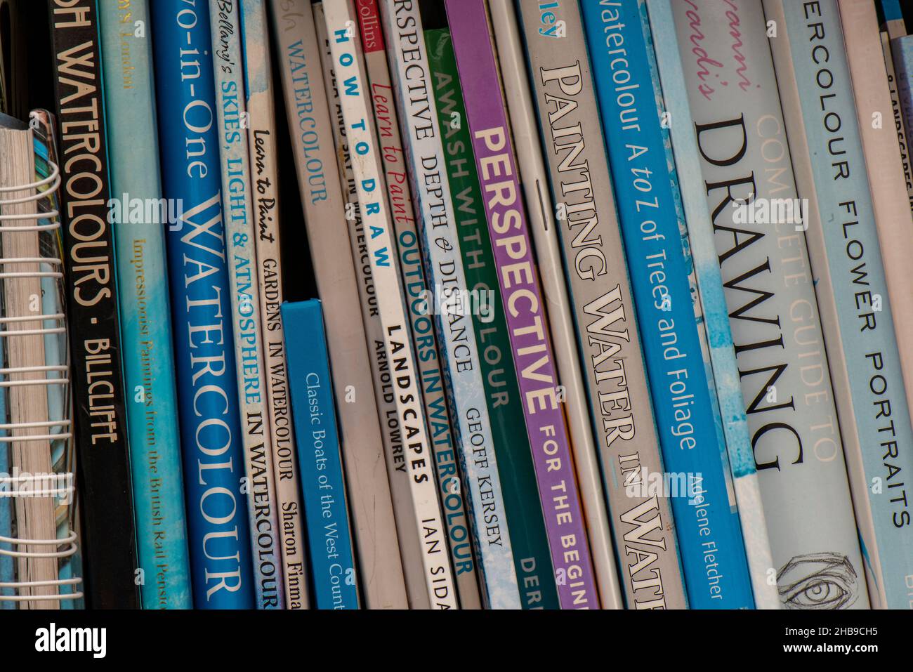 Bücher über Kunst und Zeichnung auf einem Bücherregal, Künstlerunterrichts- und Nachschlagewerke mit verschiedenen Titeln, die in einer Studie auf einem Bücherregal zusammengestapelt sind. Stockfoto