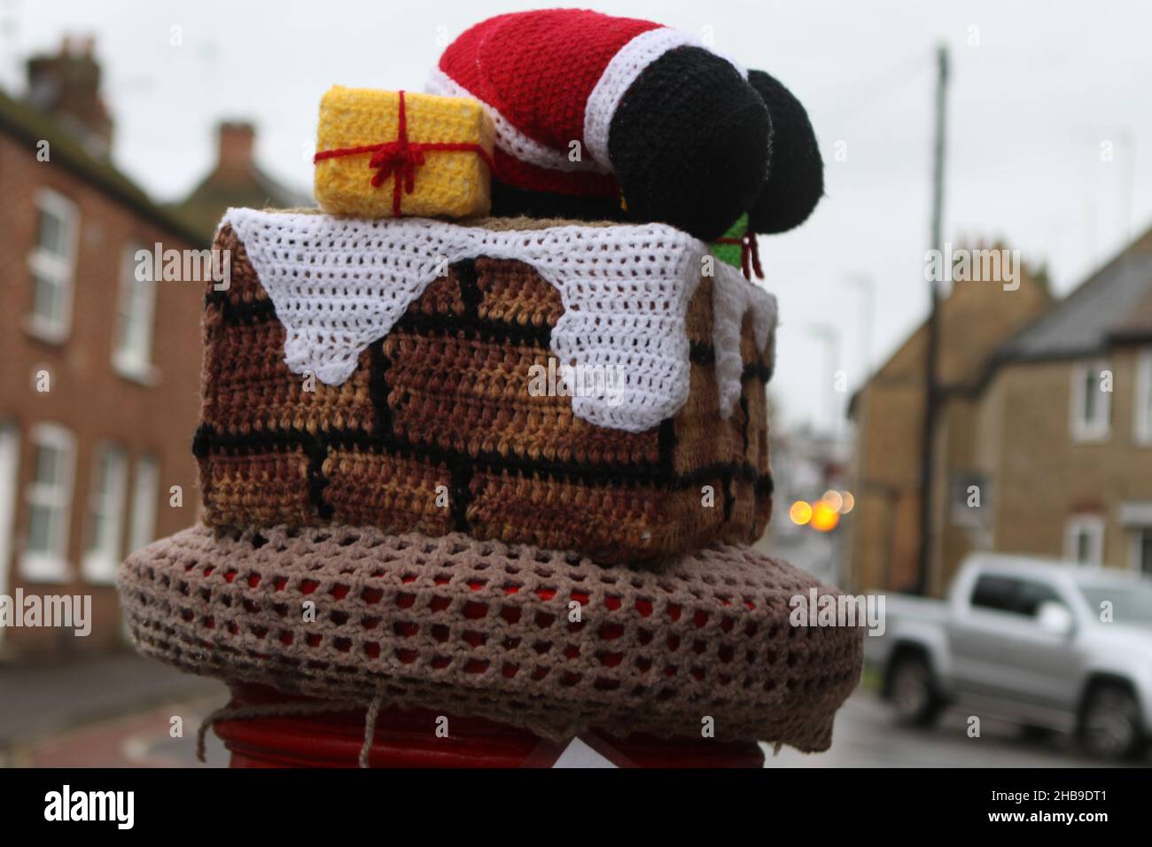 Ein Hut für einen Briefkasten in Ely, gestrickt von The Secret Yarn Bomber, mit dem Weihnachtsmann, der einen Kamin hinunterklettert Stockfoto