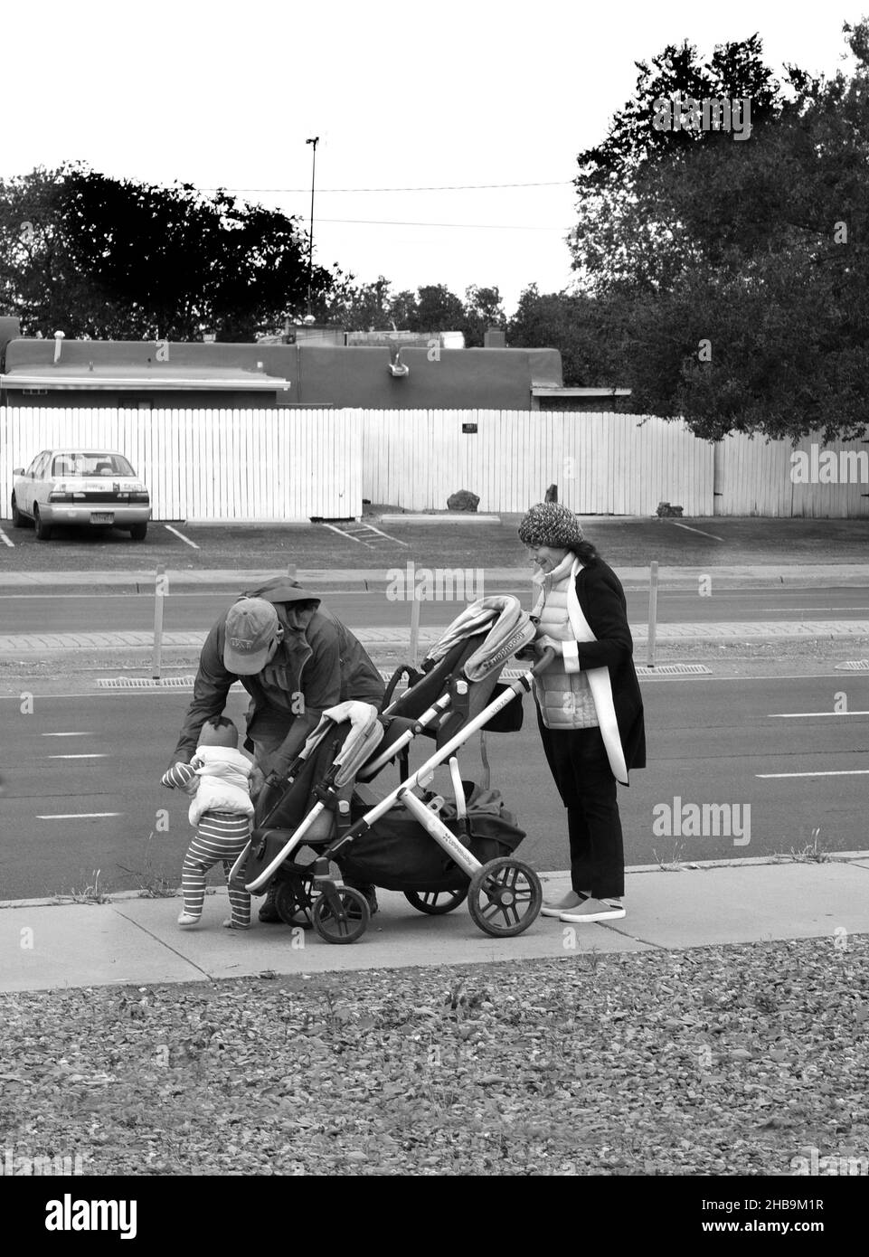 Ein Paar transportiert ein Kleinkind in einem Kinderwagen auf einem Bürgersteig in Santa Fe, New Mexico. Stockfoto