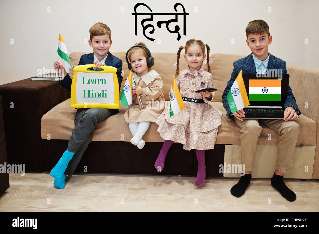 Vier Kinder zeigen die Inschrift hindi lernen. Fremdsprachenlernkonzept. Indische Flaggen. Stockfoto
