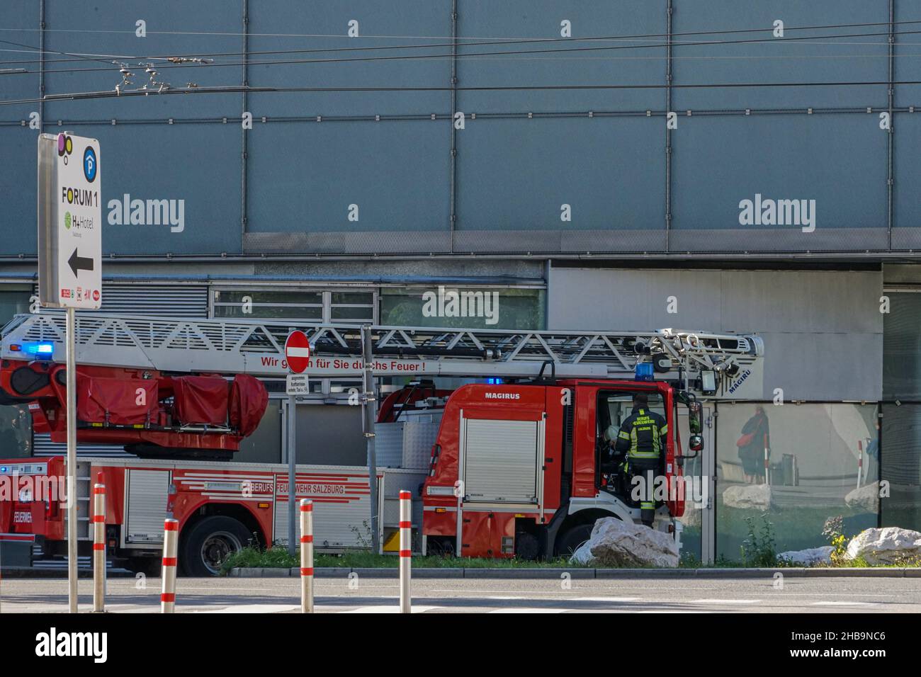 Eine Feuerwehrmaschine mit gefalteter Leiter und drehbarem blauem Licht auf einer Notfahrt in einer engen Straße in Salzburg, Österreich. Stockfoto