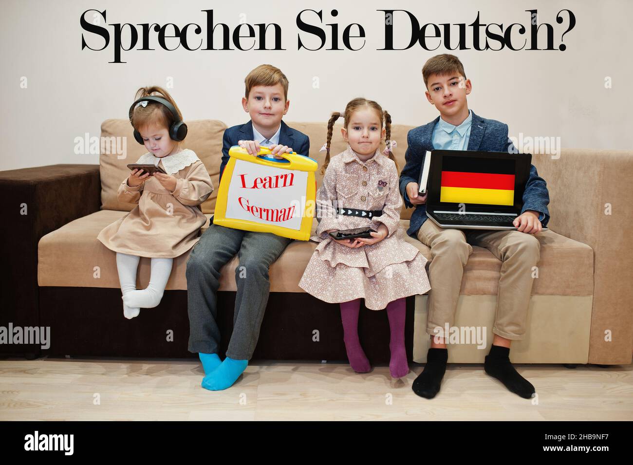 Vier Kinder zeigen die Inschrift Deutsch lernen. Fremdsprachenlernkonzept. Sagen sie Deutsch? Stockfoto