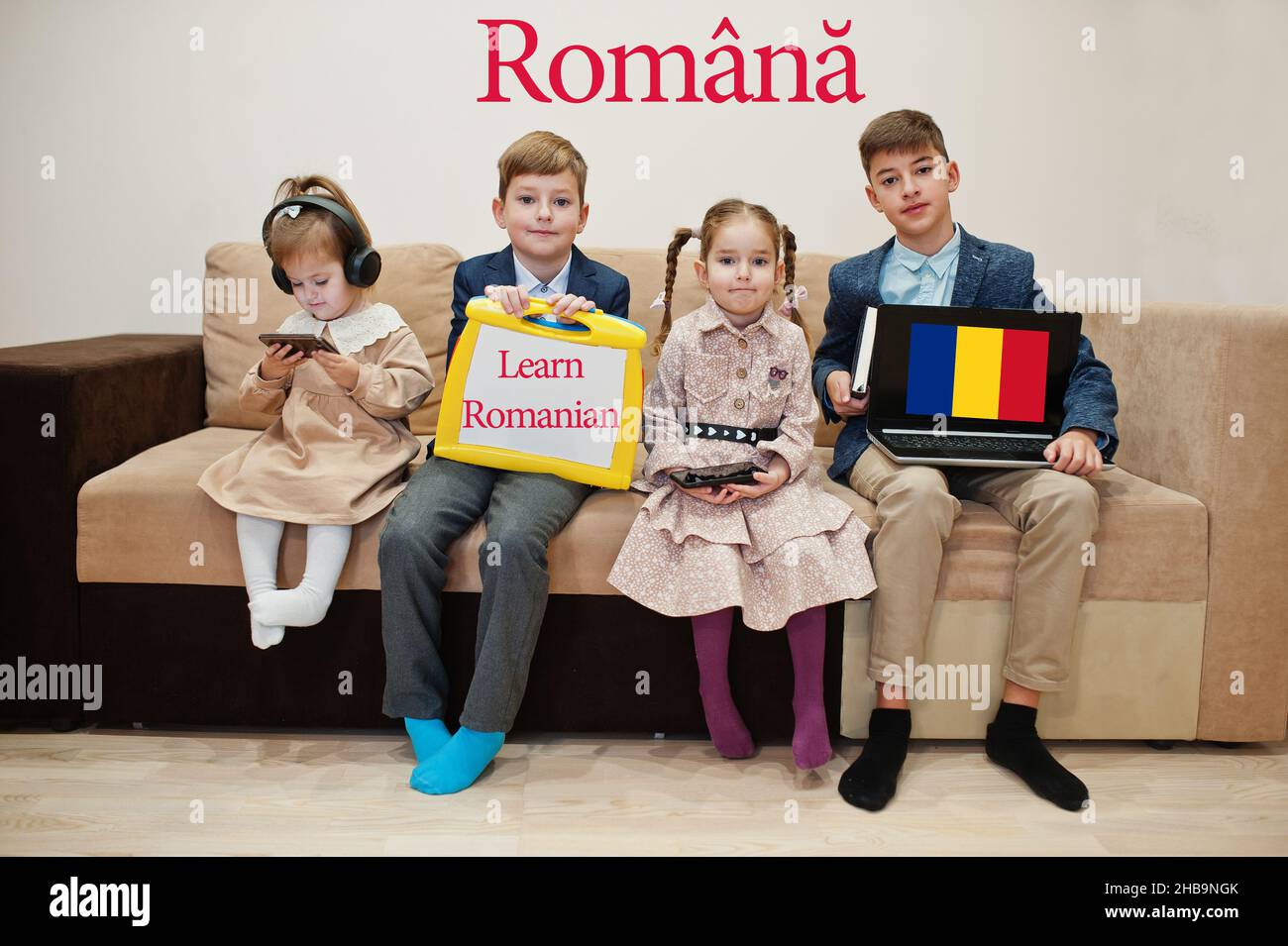 Vier Kinder zeigen die Inschrift rumänisch lernen. Fremdsprachenlernkonzept. Romana. Stockfoto
