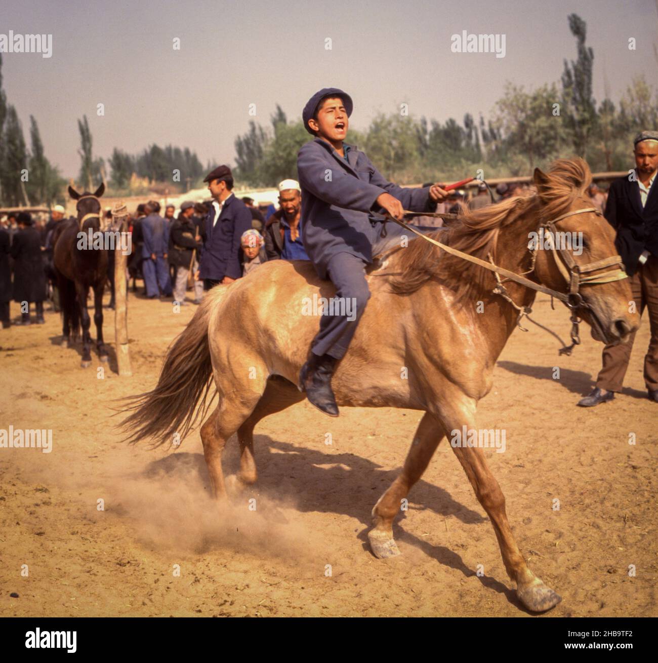 Ein Teenager-Junge testet 1988 ein Pferd auf einem Freiluftpferdemarkt in Kashgar, China. Stockfoto