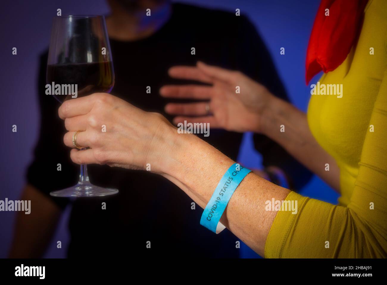 Nahaufnahme des Covid-19 Status Check-Armbands auf kaukasischen, nicht identifizierbaren Weibchen, das eine Weinklasse bei einem gesellschaftlichen Ereignis in Großbritannien hält. Stockfoto