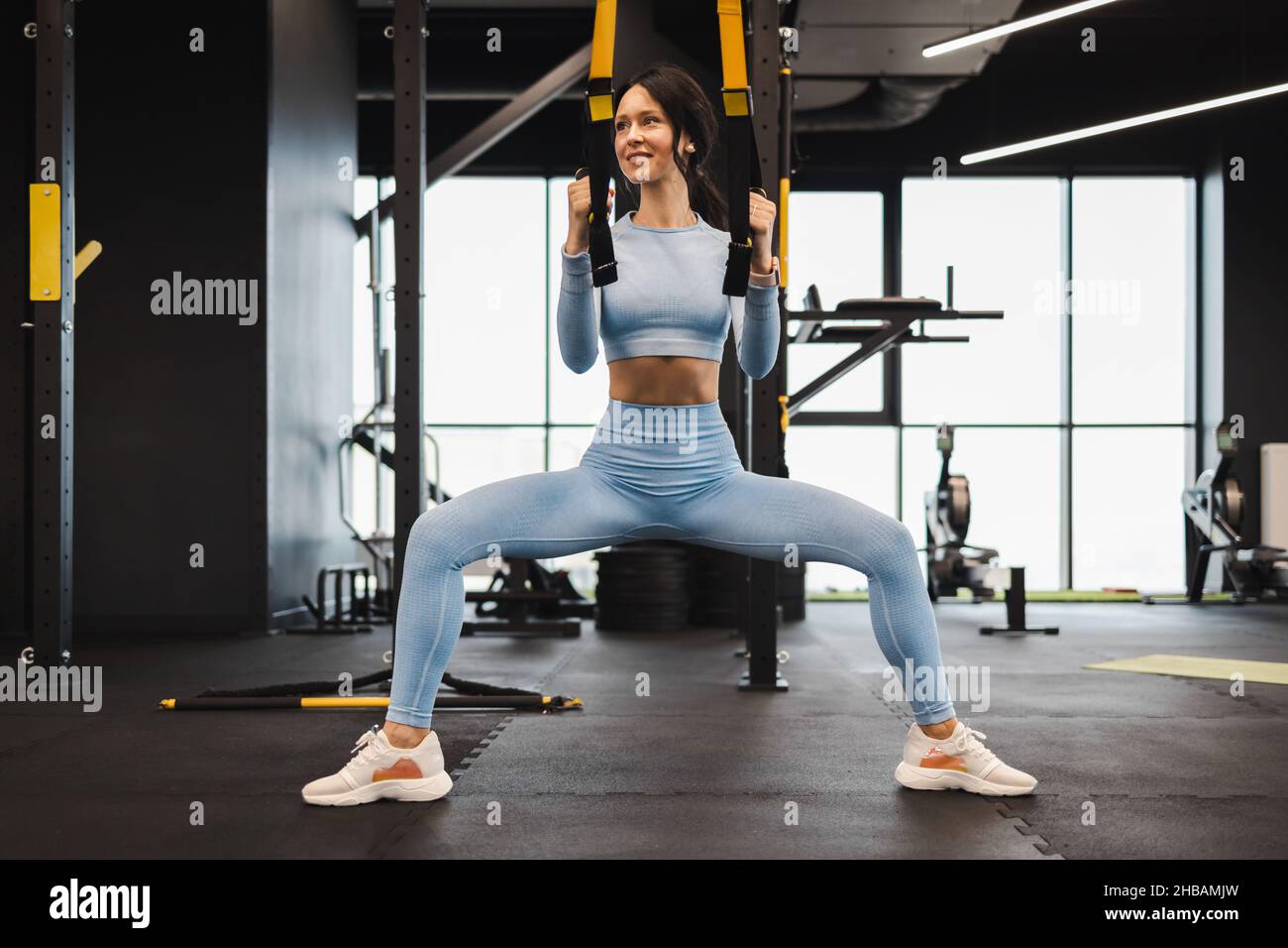 Hübsche Frau, die im Fitnessstudio mit trx-Trägern trainiert Stockfoto