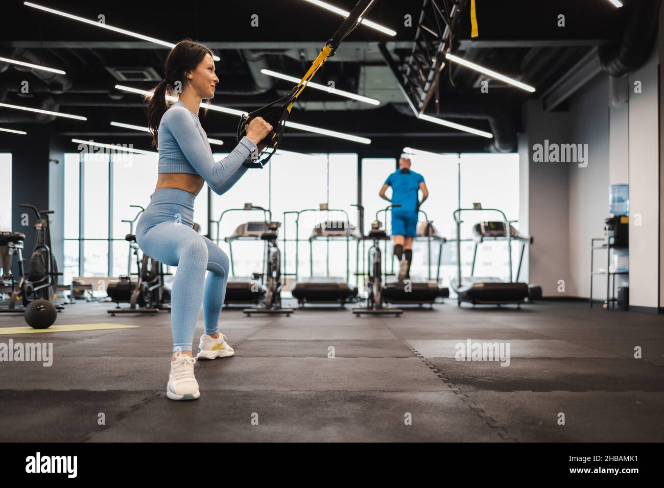 Hübsche Frau, die im Fitnessstudio mit trx-Trägern trainiert Stockfoto