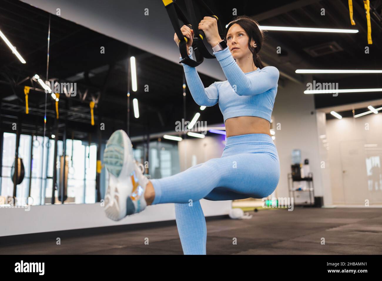 Fitness-Frau macht Knieübungen und trainiert Beine mit trx-Trägern im Fitnessstudio Stockfoto