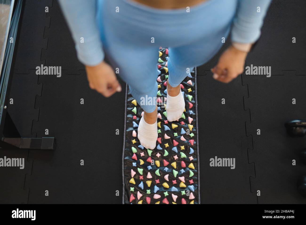 Akupunkturpunkte der Fußstimulation. Frau steht auf orthopädischer Fußmassagematte. Massagewrug mit bunten Steinen Stockfoto