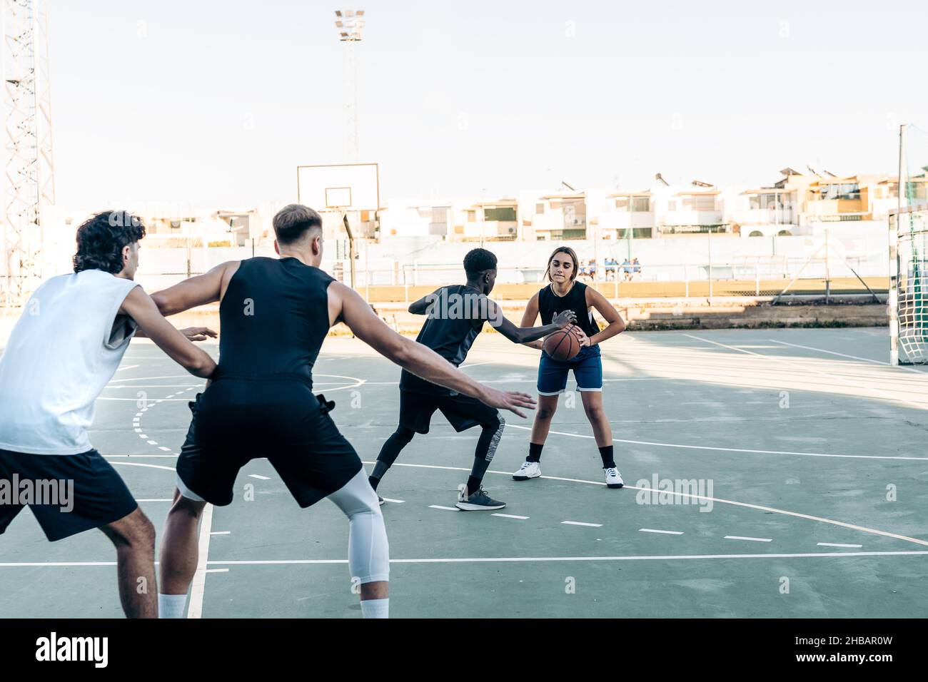 Frau und drei Männer spielen Basketball in einem städtischen Gericht Stockfoto
